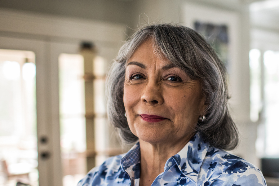 Mature grey haired woman smiling with look of enjoyment and confidence on her face.