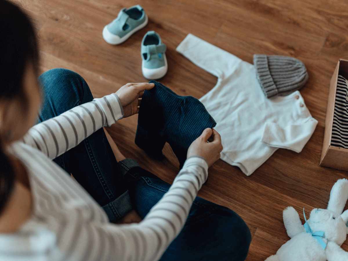 Newly pregnant woman sorts through a box of baby clothes