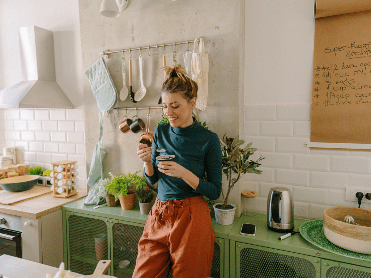 Young woman eating yogurt in her kitchen.