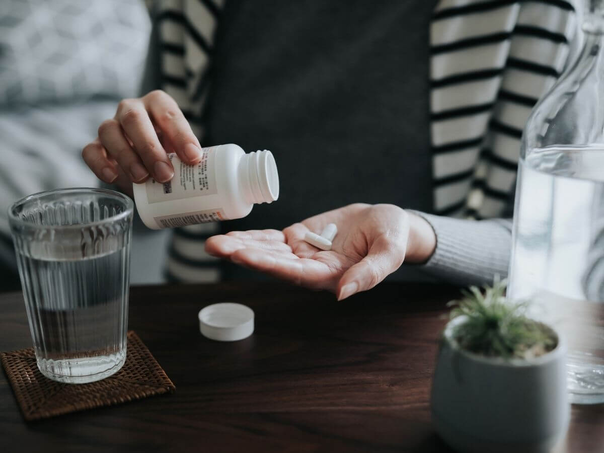 Close up photo of a woman pouring medication from the bottle into her hand.