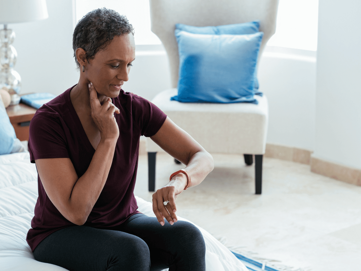 Woman sitting on the couch checking her pulse.