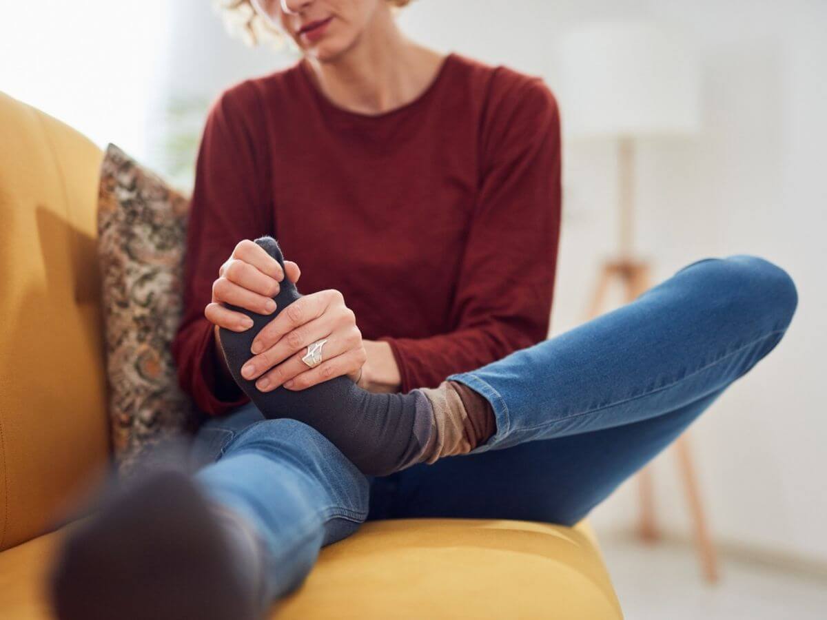 Close up of a woman holding and looking at her foot.