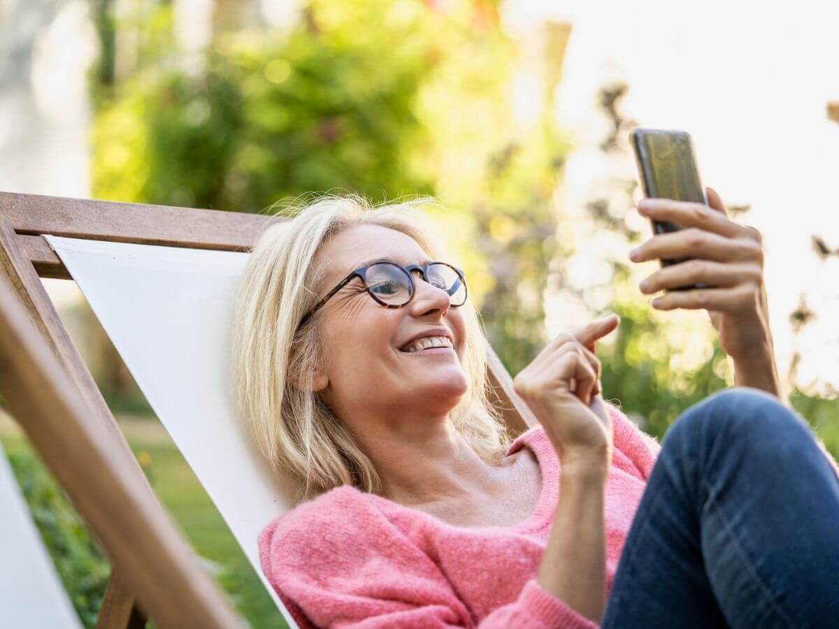 Middle aged woman reads on her smartphone outside