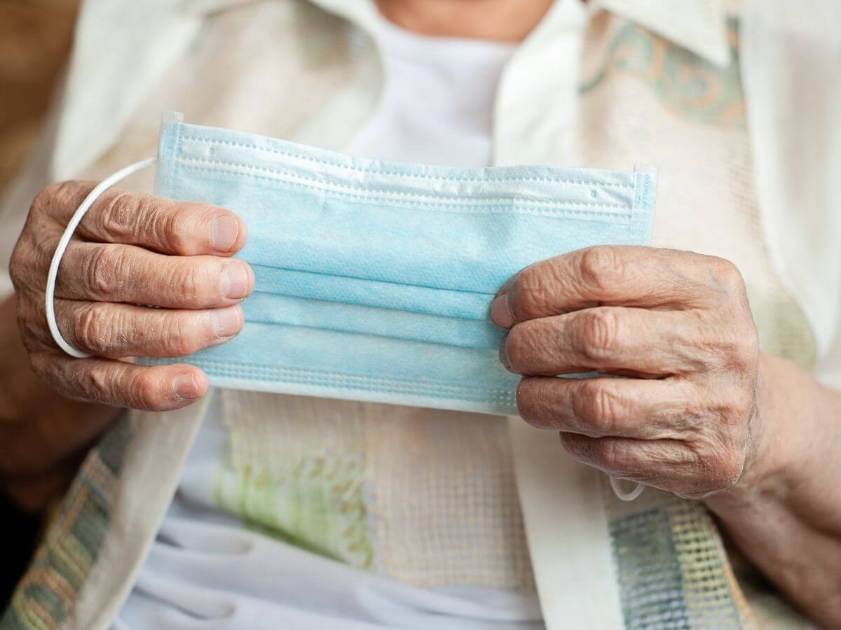 Extreme close up of an older woman's hands holding a disposable mask