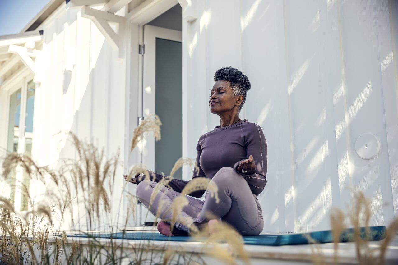 Middle aged woman meditating outside her home